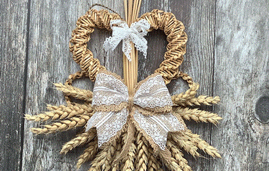 A decorative woven wheat wall hanging with two white lace bows.