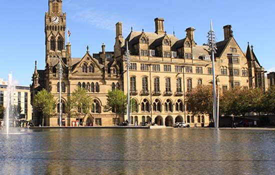 A large building (Bradford Town Hall) stands the other side of a pool of water