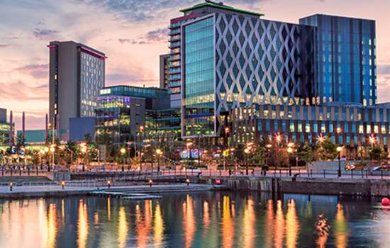Large modern buildings viewed across water at sunset