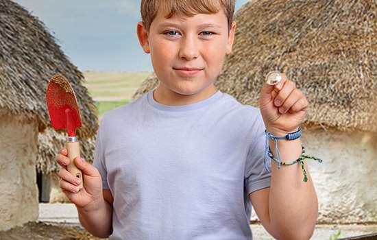 Boy holding trowel and object he has excavated