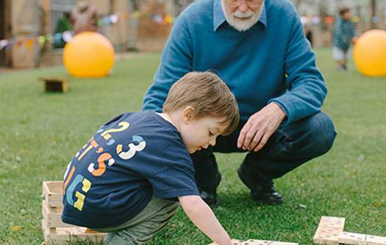 A boy and a man play with oversized dominoes
