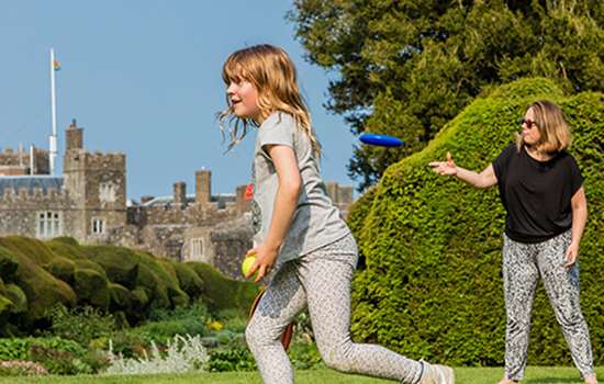 A girl and woman play with a frisbee with Walmer Castle in the background